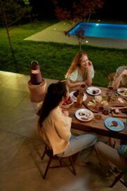 Friends enjoying dinner in the garden as LG XBOOM 360 elevates the comfortable atmosphere