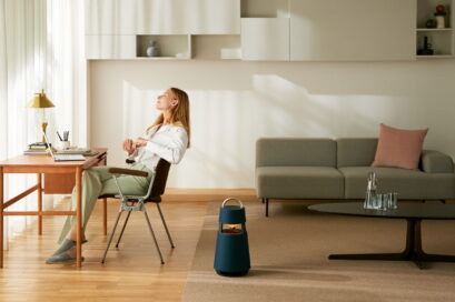 A woman working at her desk with LG XBOOM 360 on the floor next to her