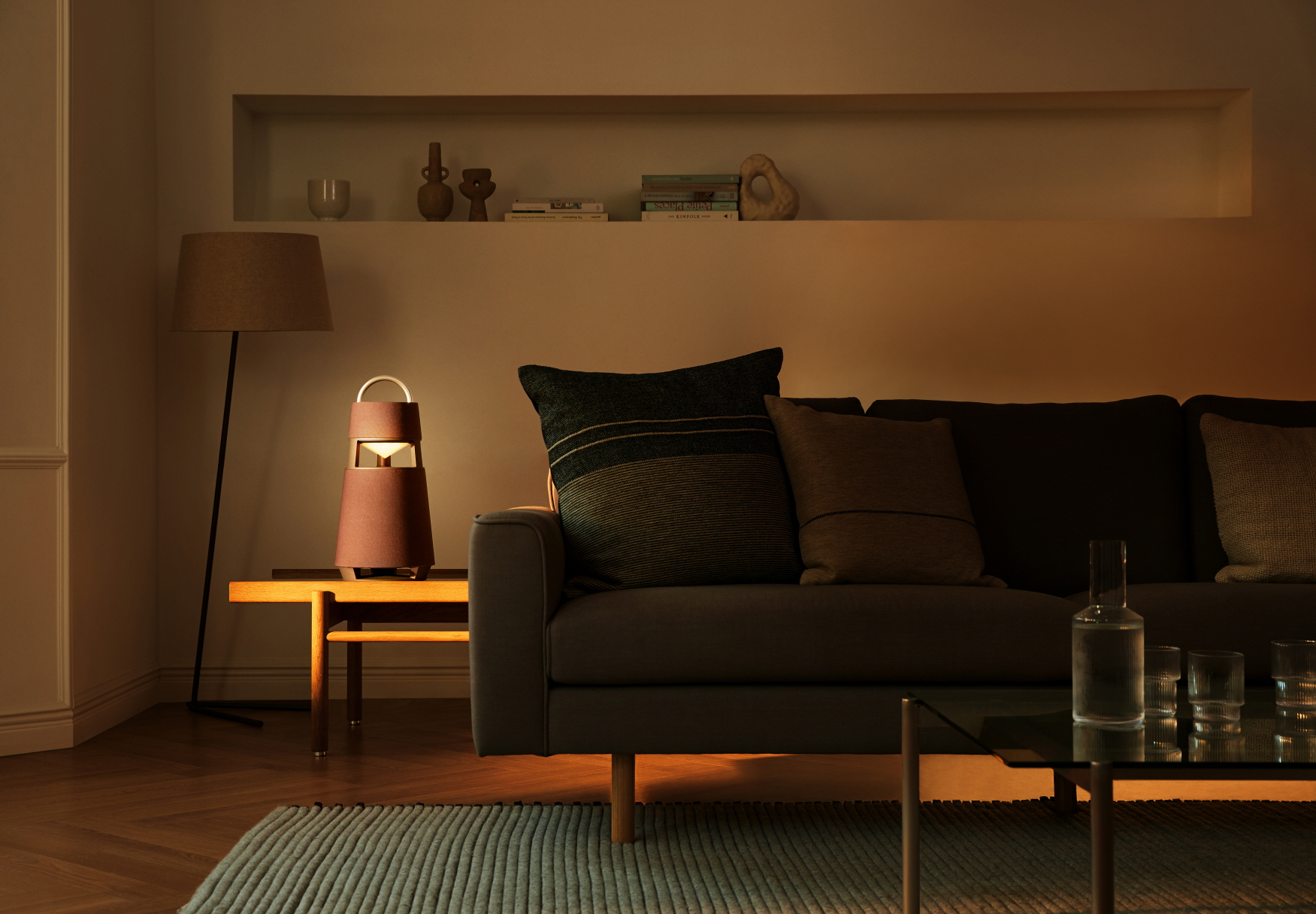 LG XBOOM 360 speaker on the side table of a dark living room as it gives off sun-like light