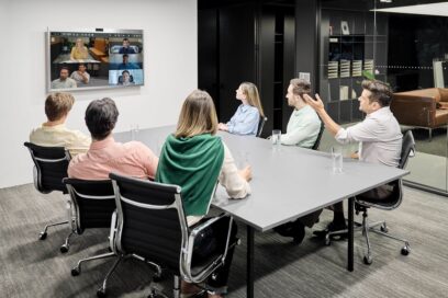 People are gathered in a meeting room watching One:Quick Works’ screen