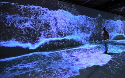 A visitor fully immersed in the white and blue waves being realistically reproduced through an art installation utilizing LG OLED displays