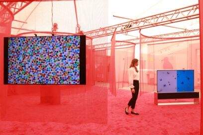 A visitor admiring the colorful artwork being displayed on LG OLED TV at an art exhibition with a red theme