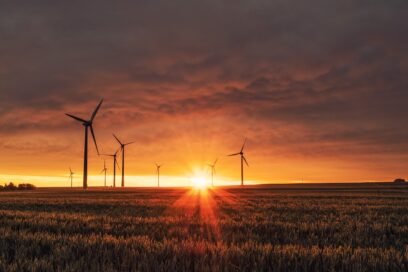 A large field with several wind turbines during a beautiful sunset.
