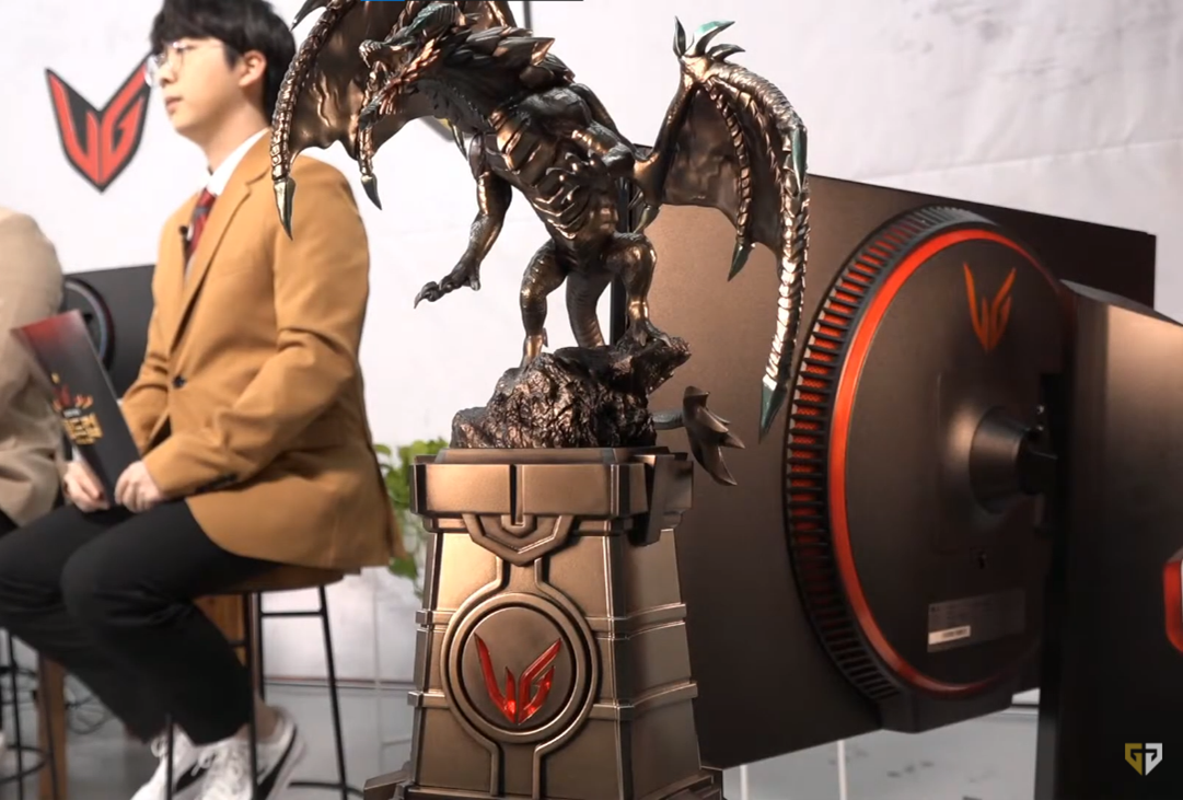 The LG UltraGear LoL Cup tournament trophy in the form of a dragon with the UltraGear monitor and e-sportscasters behind.