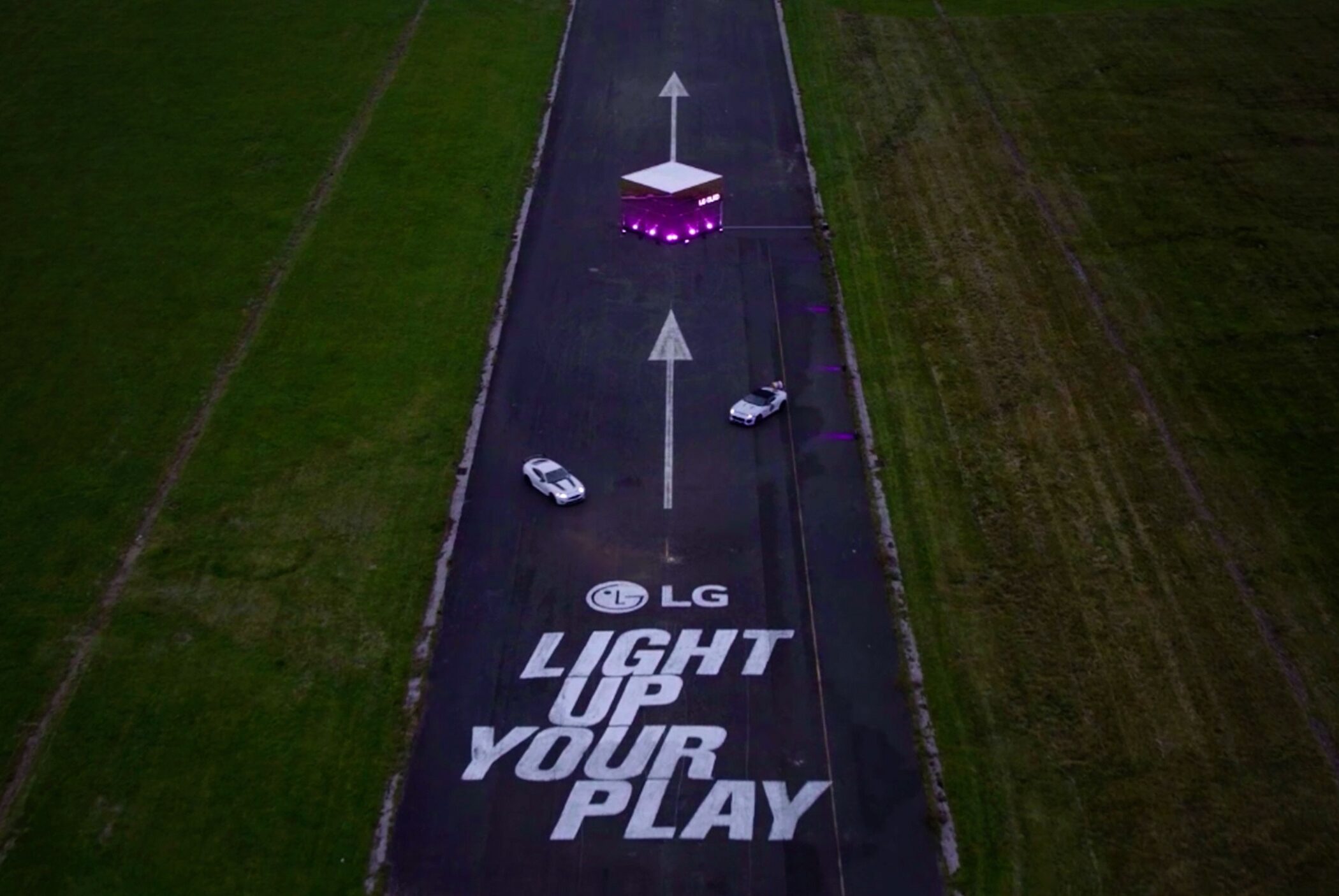 A photo of a road with a phrase "LG LIGHT UP YOUR PLAY" where two cars are racing