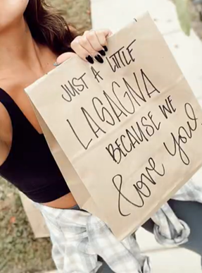 A Give LG Lasagna Love Challenge participant holding a bag with the phrase ‘Just a little lasagna because we love you’ printed on it.