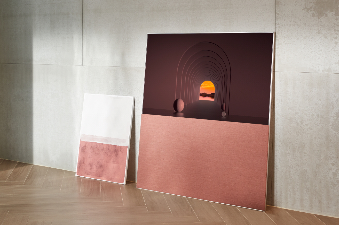 LG’s redwood Objet TV leaning against the wall as it displays artwork in its Full View mode while harmonizing with a painting beside it.