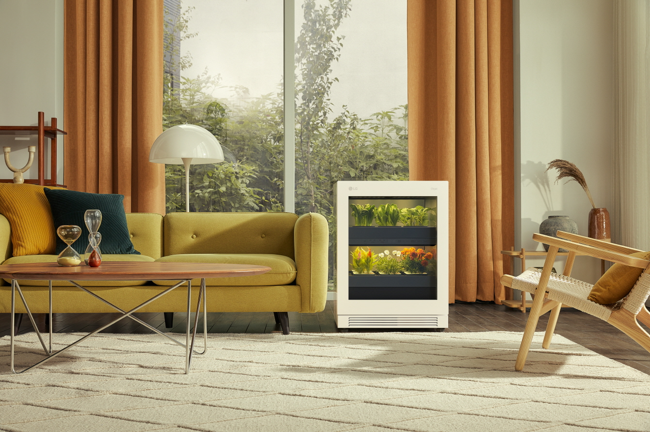 A front view of LG tiiun Nature Beige indoor gardening appliance next to a sofa in a living room.