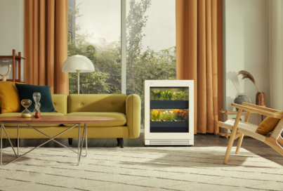 A front view of LG tiiun Nature Beige indoor gardening appliance next to a sofa in a living room.