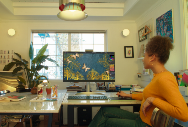 A woman is editing an image using LG UltraFine monitor and a mousepad