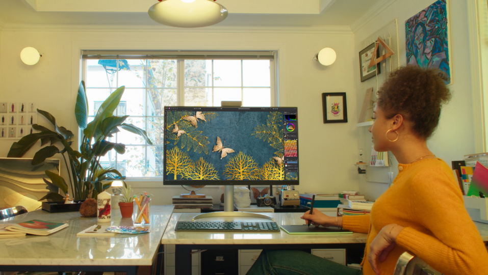 A woman is editing an image using LG UltraFine monitor and a mousepad