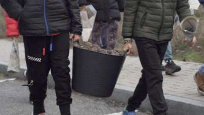 Children carrying a large bucket of seed balls they made with the help of LG employees.