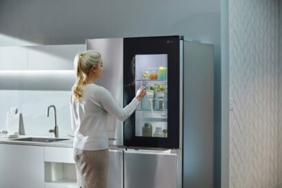 A woman knocking on her LG Door-in-Door refrigerator’s window to look inside without opening the door