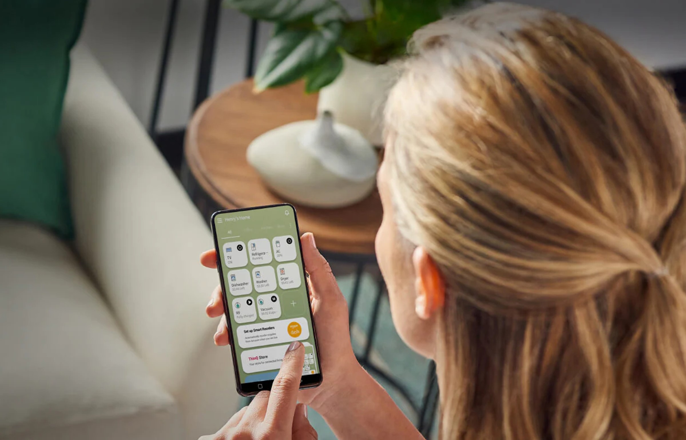 A woman using the LG ThinQ app to control her LG InstaView refrigerator.