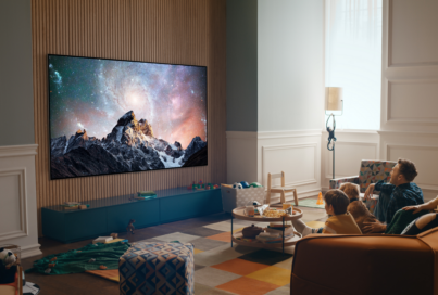 A family together in their living room enjoying spectacular natural landscape images on their wall-mounted 2022 LG OLED TV.