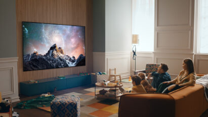 A family together in their living room enjoying spectacular natural landscape images on their wall-mounted 2022 LG OLED TV.