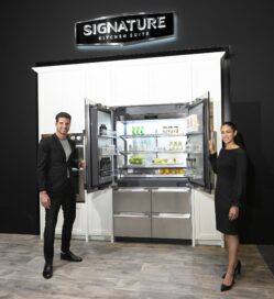 A man and a woman are holding the door of the Signature Kitchen Suite 48-inch French Door refrigerator opened