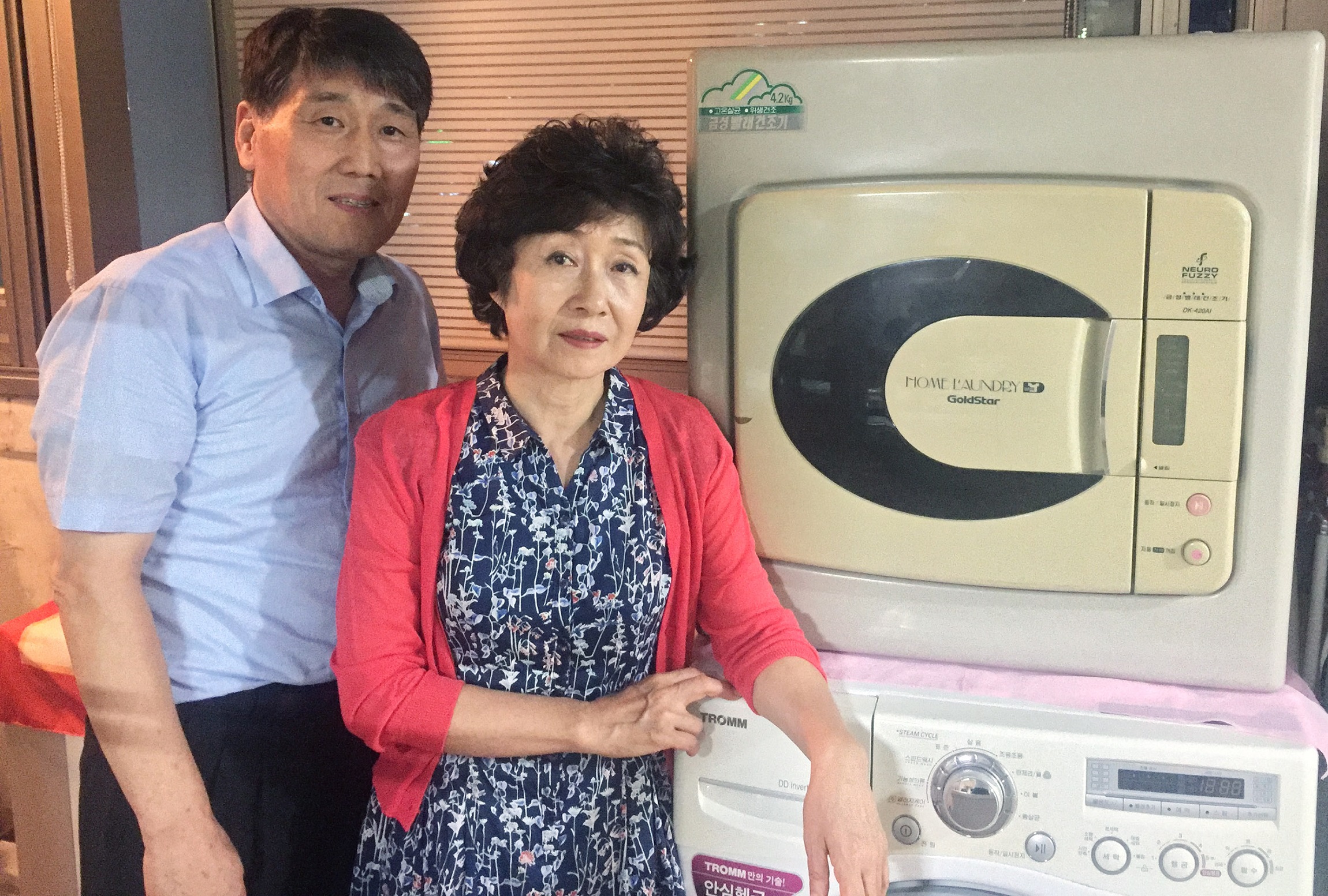 The owners of a 20-year-old Goldstar dryer posing with their old machine