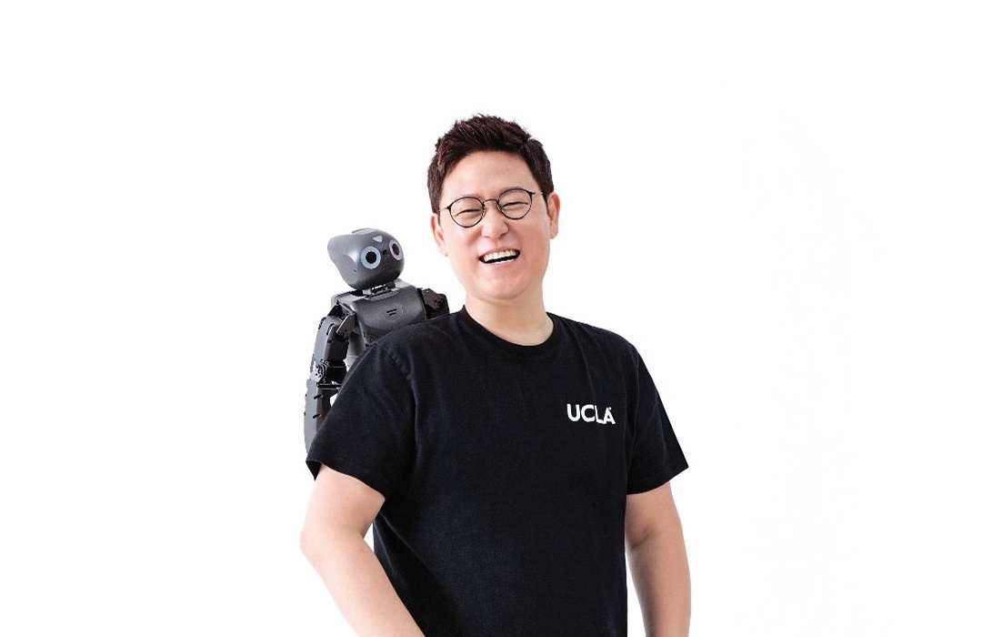 A photo of Dr. Dennis Hong with a robot on his shoulder