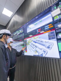 The workers at the Lighthouse Factory in Changwon are looking at the screen of virtual factory made by an Intelligent process system. (Vertical)