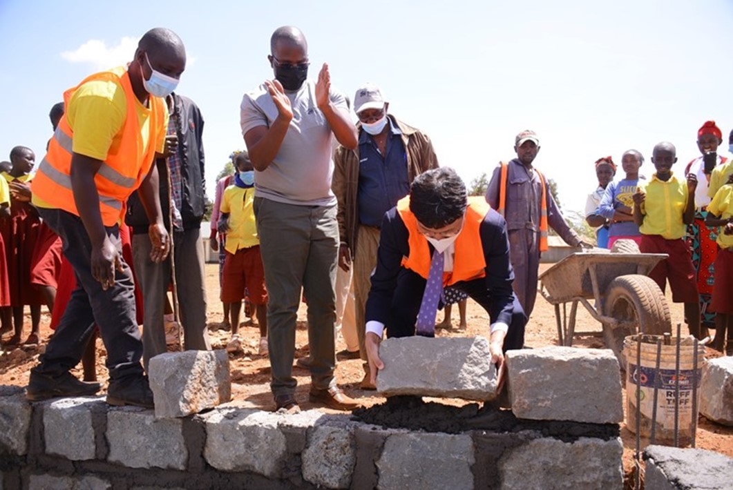 LG Electronics East Africa Managing Director Kim Sa-nyoung lays a stone to commence construction of ablution blocks at Mbombo Primary School, with HFH Senior Program Manager Nixon Otieno and Mbombo Primary School Headteacher Mwangi Thumbi looking on.