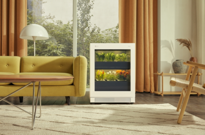 A front view of LG tiiun Nature Beige indoor gardening appliance next to a sofa in a living room.