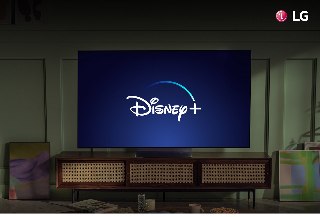 An LG TV in a living room displaying the Disney+ logo to celebrate the streaming service coming to more LG Smart TVs.