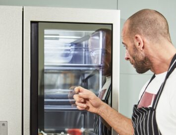 Chris Denny knocking on the door of LG InstaView refrigerator to demonstrate its special feature