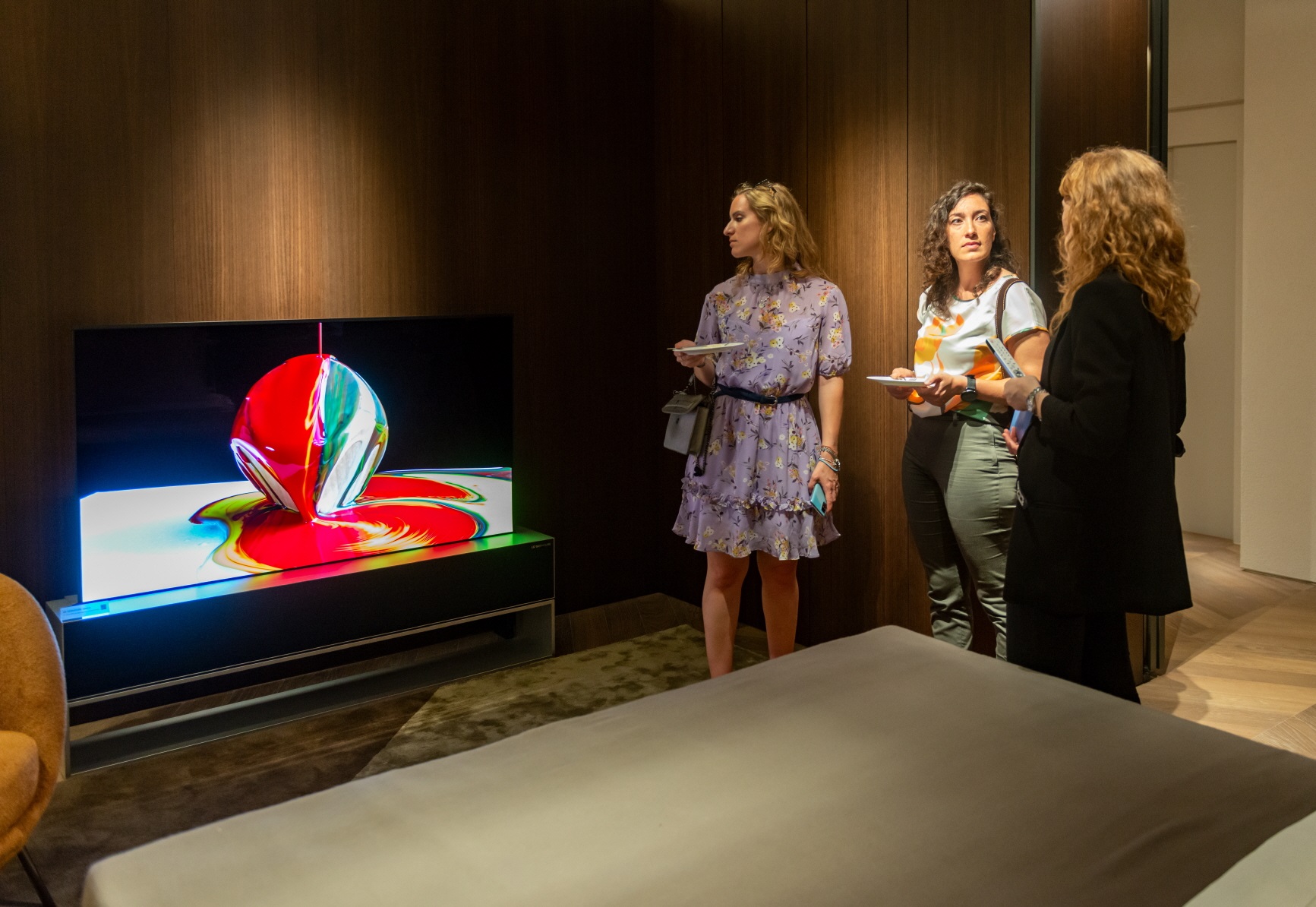 Three visitors taking a closer look at LG OLED R during Milan Fashion Week 2022