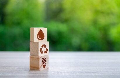 Icon representing a water droplet, a recycling logo and a light bulb are engraved on each of the three wooden cubes and placed on the table