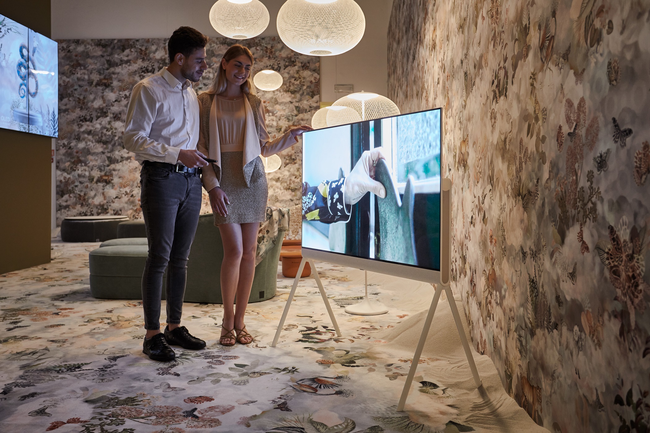 Two visitors taking a closer look at LG OLED Objet Collection, Posé (LX1), displayed at Salone dei Tessuti during Milan Design Week 2022