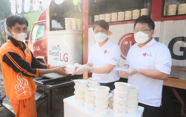 Lee Taijin, President of LG Electronics Indonesia, and Kris Lee, Product Marketing Director of Home Appliances LG Electronics Indonesia, serve food to a waste disposal worker in Jakarta