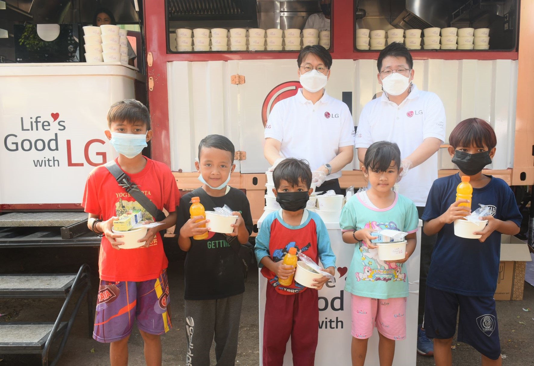 Lee Taijin, President of LG Electronics Indonesia, and Kris Lee, Product Marketing Director of Home Appliances LG Electronics Indonesia, serve food to children in Jakarta