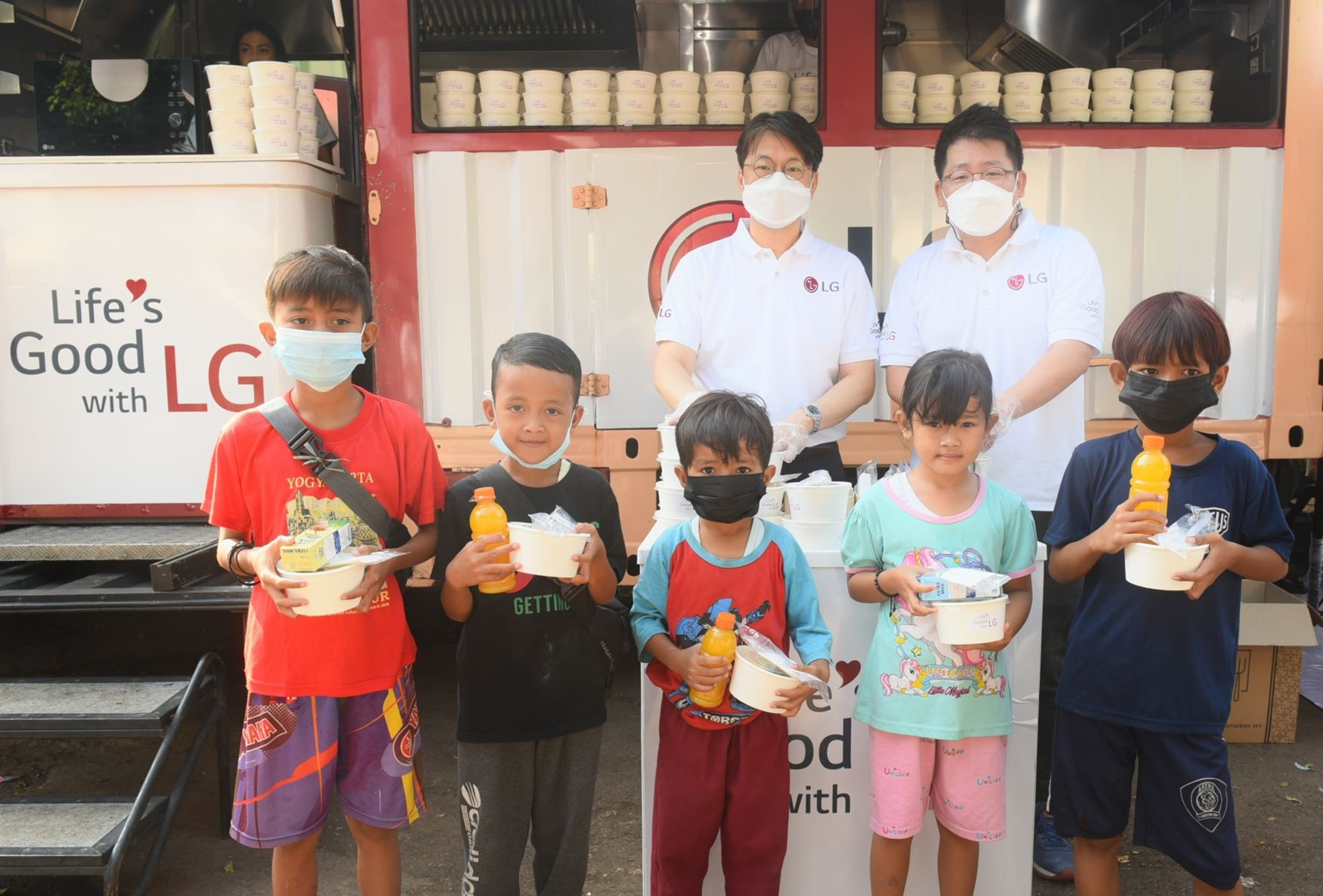 Lee Taijin, President of LG Electronics Indonesia, and Kris Lee, Product Marketing Director of Home Appliances LG Electronics Indonesia, serve food to children in Jakarta