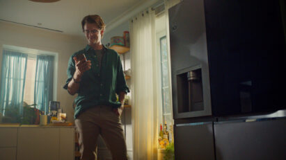 A man standing in front of LG Instaview refrigerator and looking at his smartphone