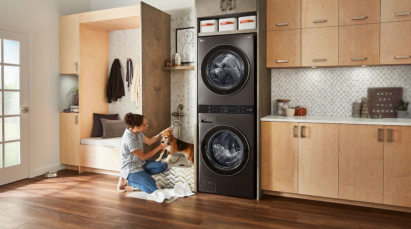 A woman gives her pet dog a shower next to a fitted LG WashTower in black