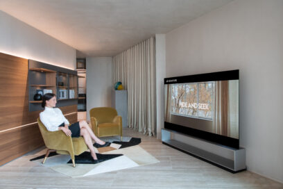 A female sitting on a comfortable chair and looking at the LG SIGNATURE OLED R displayed at Molteni&C flagship store in Amsterdam.