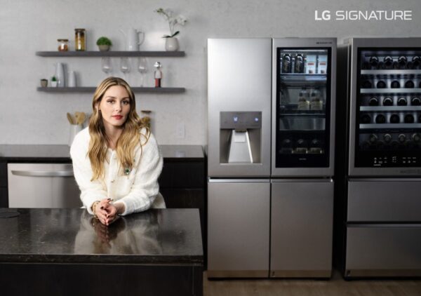 Olivia Palermo is leaning on the LG SIGNATURE Washer/Dryer Combo, positioned between a hanger and laundry trolley
