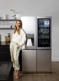 Olivia Palermo is posing in front of the LG SIGNATURE InstaView™ Door-in-Door® Refrigerator.