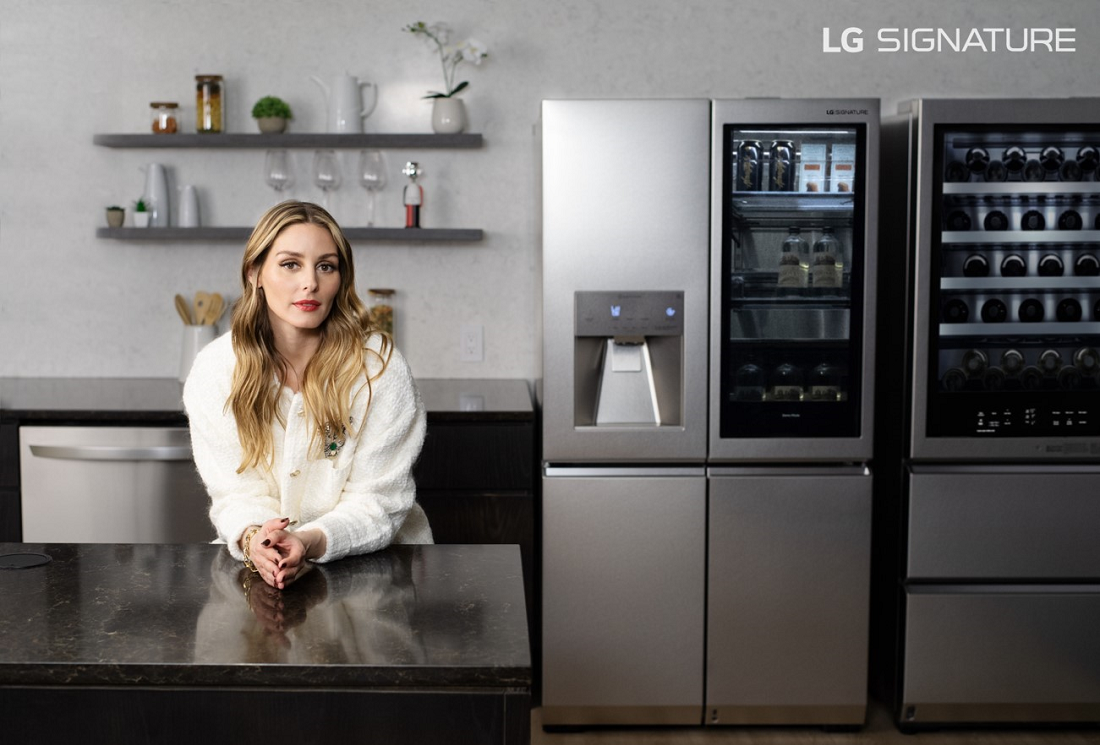 Olivia Palermo is perching over the kitchen counter next to the LG SIGNATURE InstaView™ Door-in-Door® Refrigerator