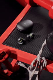 LG TONE Free fit earbuds inside the vibrant UVnano charging case in a gym next to weights and boxing gloves