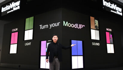 A man in the middle is indicating at one of MoodUPTM refrigerators in front of the LED wall at IFA 2022