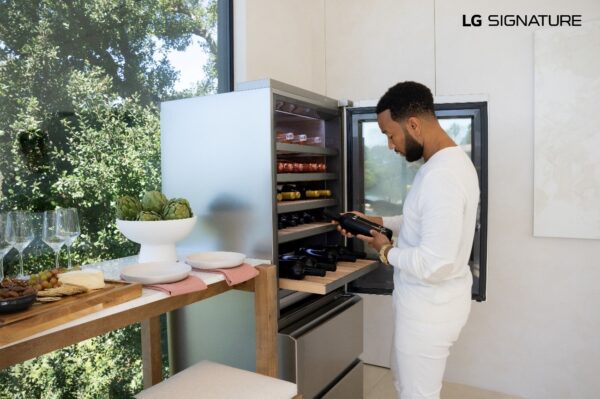 John Legend examining a bottle of wine after taking it from his LG SIGNATURE Wine Cellar