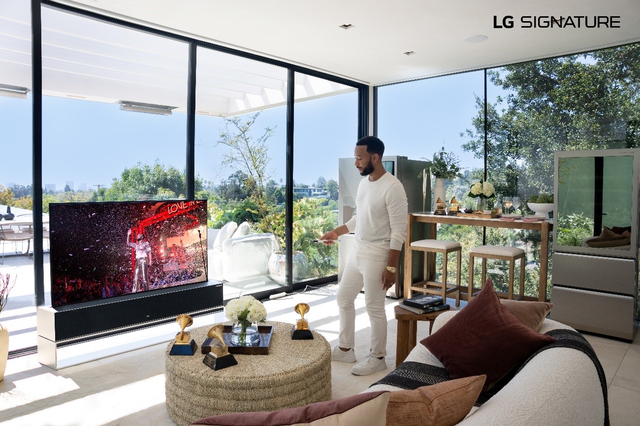 John Legend pointing the remote at his LG SIGNATURE OLED R TV