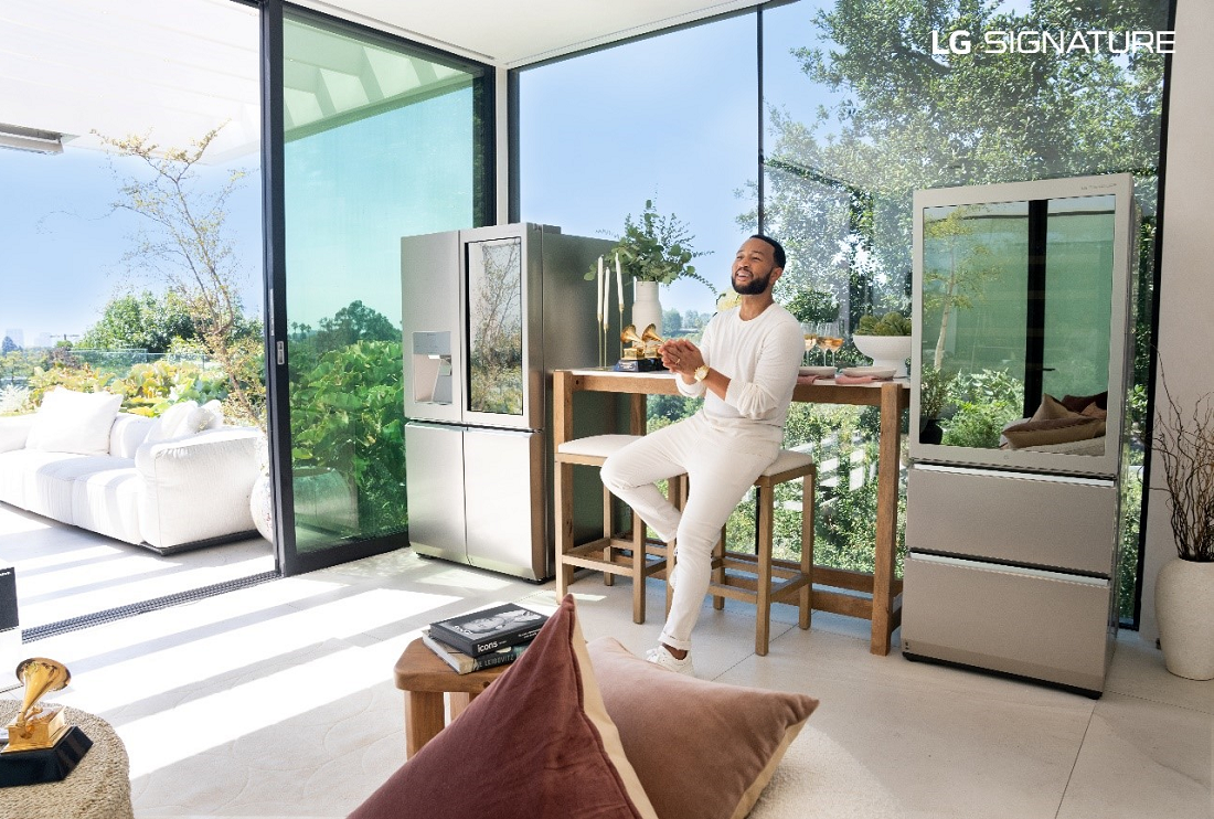 John Legend sitting on a stool between the LG SIGNATURE InstaView Door-in-Door refrigerator and LG SIGNATURE Wine Cellar