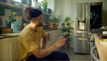 A man using his phone in the kitchen