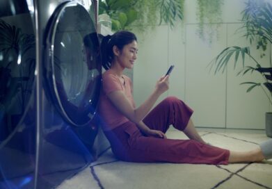 A woman using her phone while leaning against LG Washer