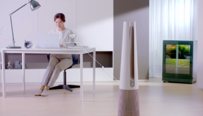 LG PuriCare AeroTower and LG tiiun installed in a space where a woman is working with a laptop on a desk