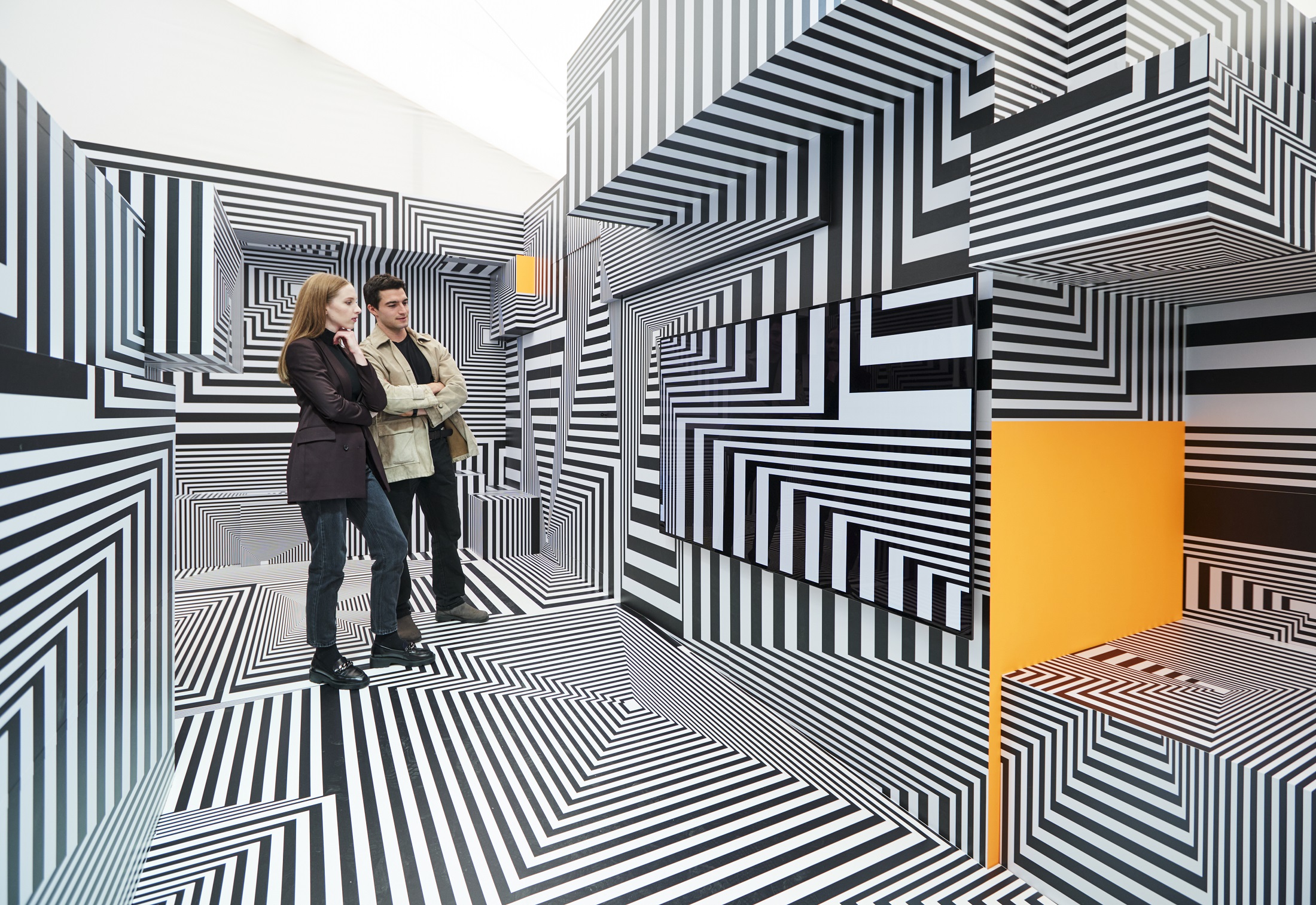 Two visitors taking a closer look at LG OLED-powered “Into the Maze” installation by the German artist, Tobias Rehberger
