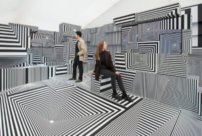 Two visitors posing at LG OLED-powered “Into the Maze” installation by the German artist, Tobias Rehberger